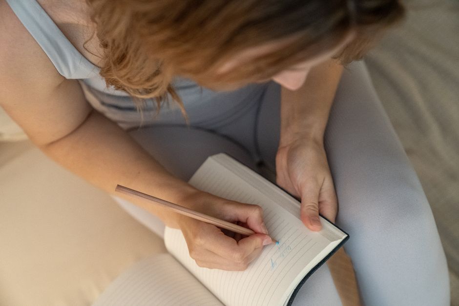 Bir kişi evde sağlık günlüğünü tutarken not alıyor