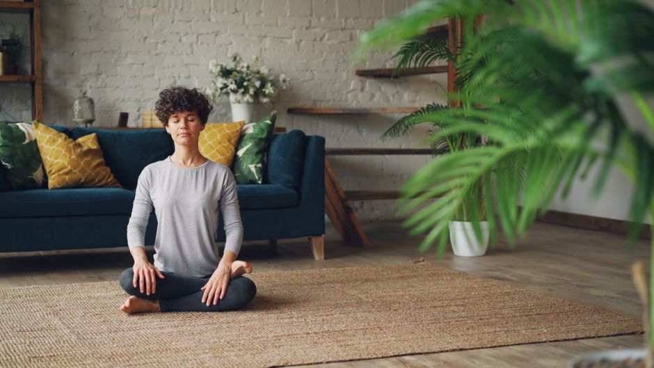 Evde mindfulness uygulamasına odaklanan sakin bir kişi meditasyon yapıyor